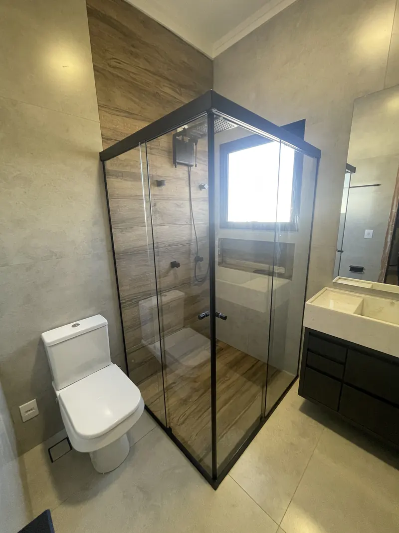 Banheiro de suíte com box de vidro e bancada