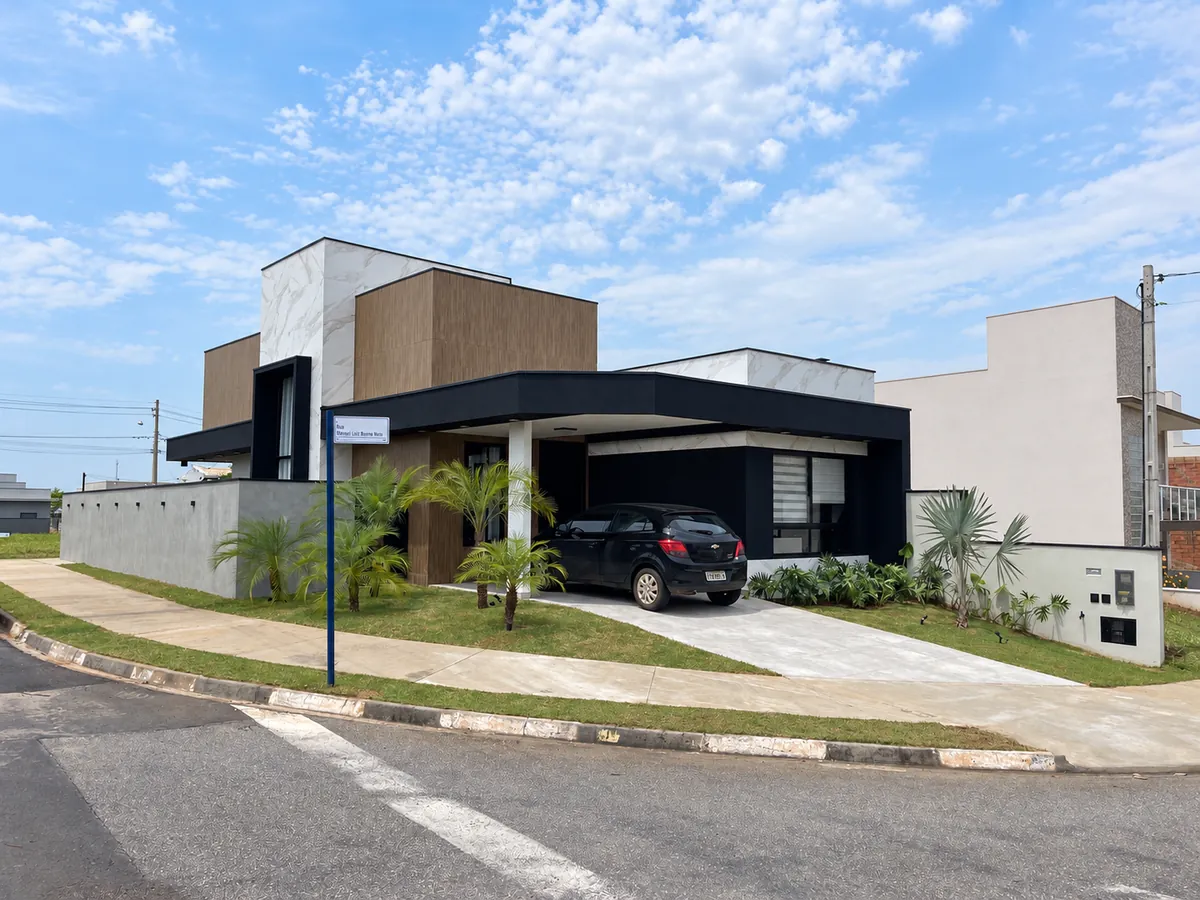 Casa térrea de esquina com volumes em porcelanato e marquise preta sobre a garagem